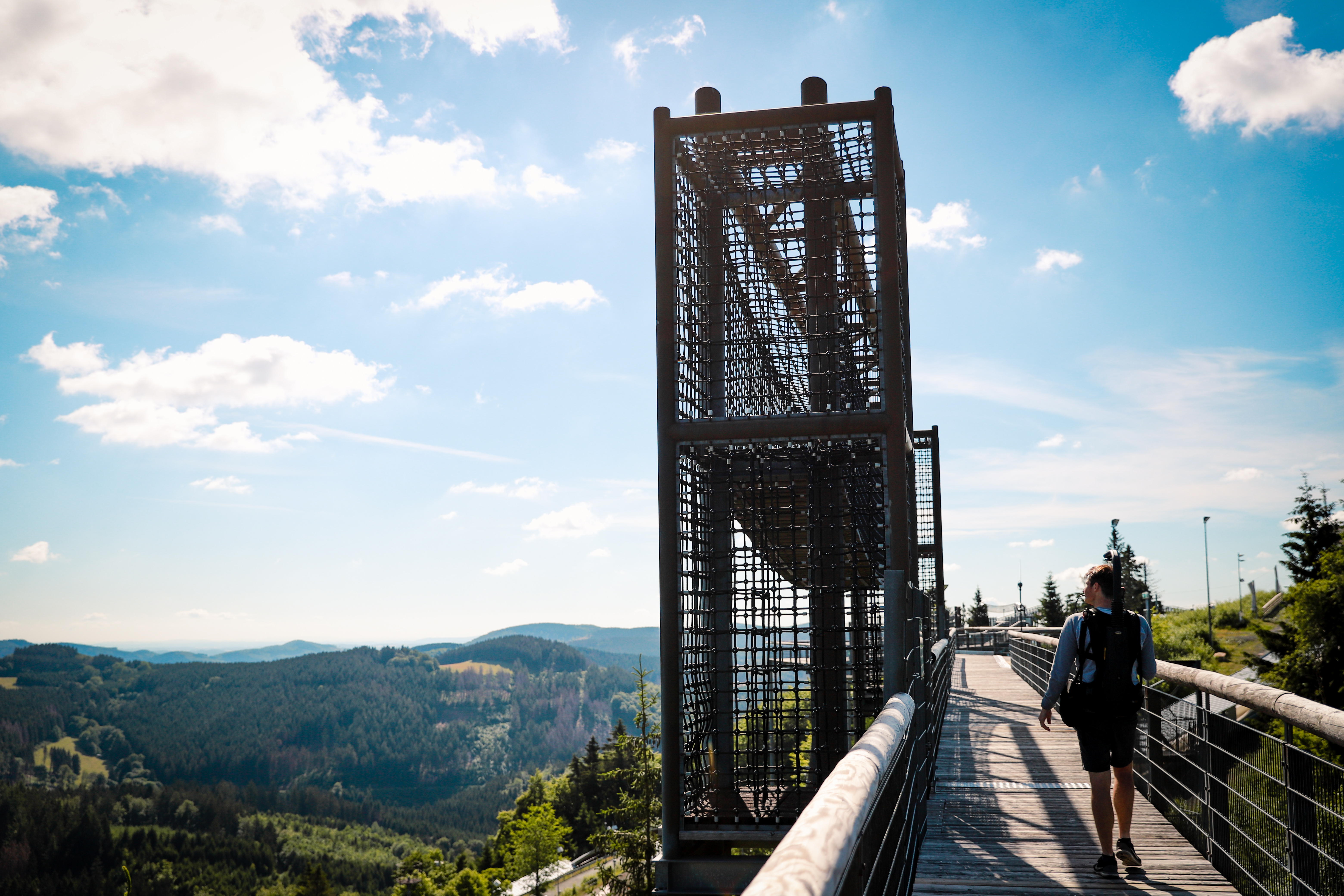 Ein Kletterelement auf der Panorama Erlebnisbrücke mit Wäldern, Bergen und blauem Himmel im Hintergrund. Ein Kletterelement auf der Panorama Erlebnisbrücke mit Wäldern, Bergen und blauem Himmel im Hintergrund.