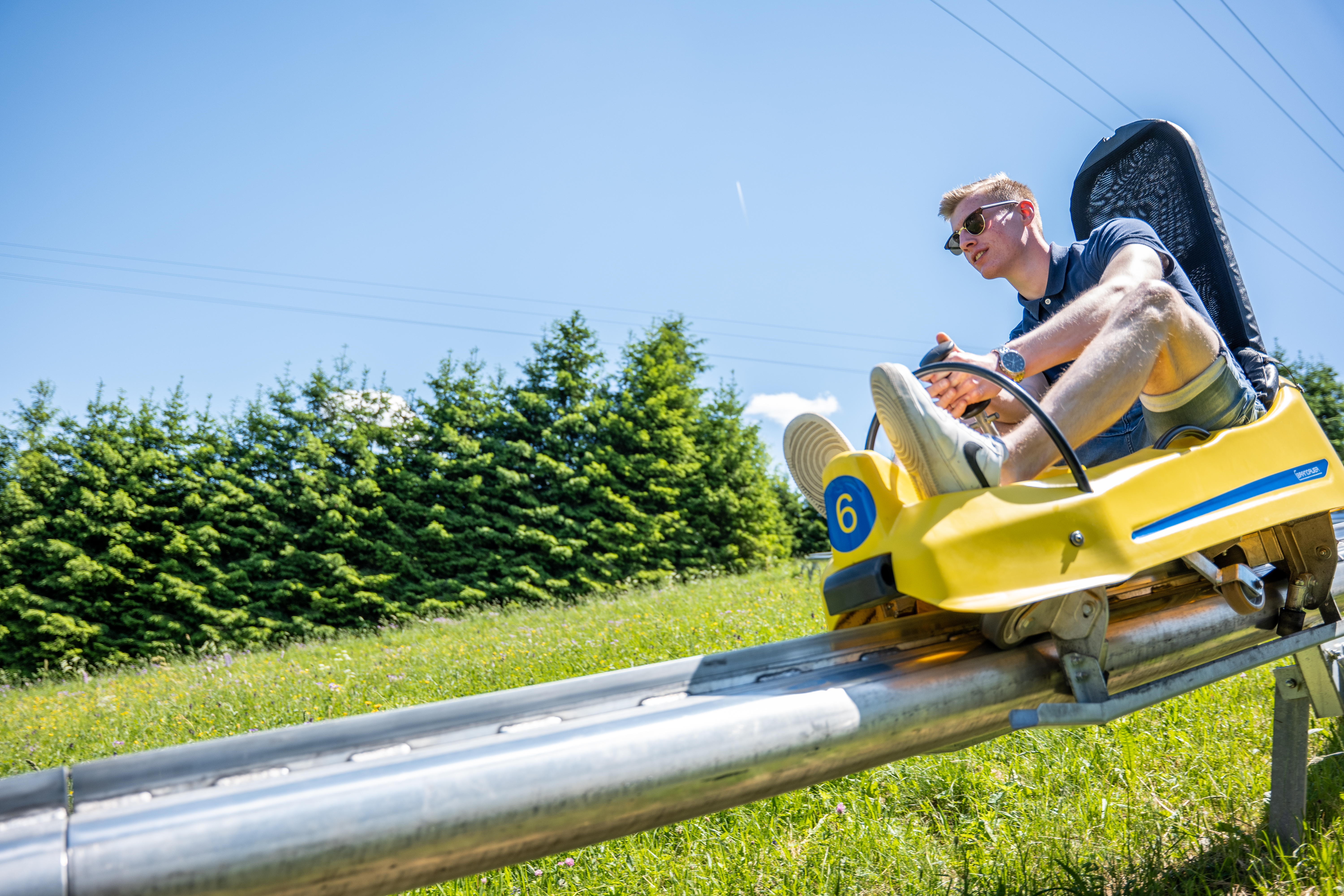Ein Mann fährt auf einem Rodelschlitten eine Sommerrodelbahn hinab.